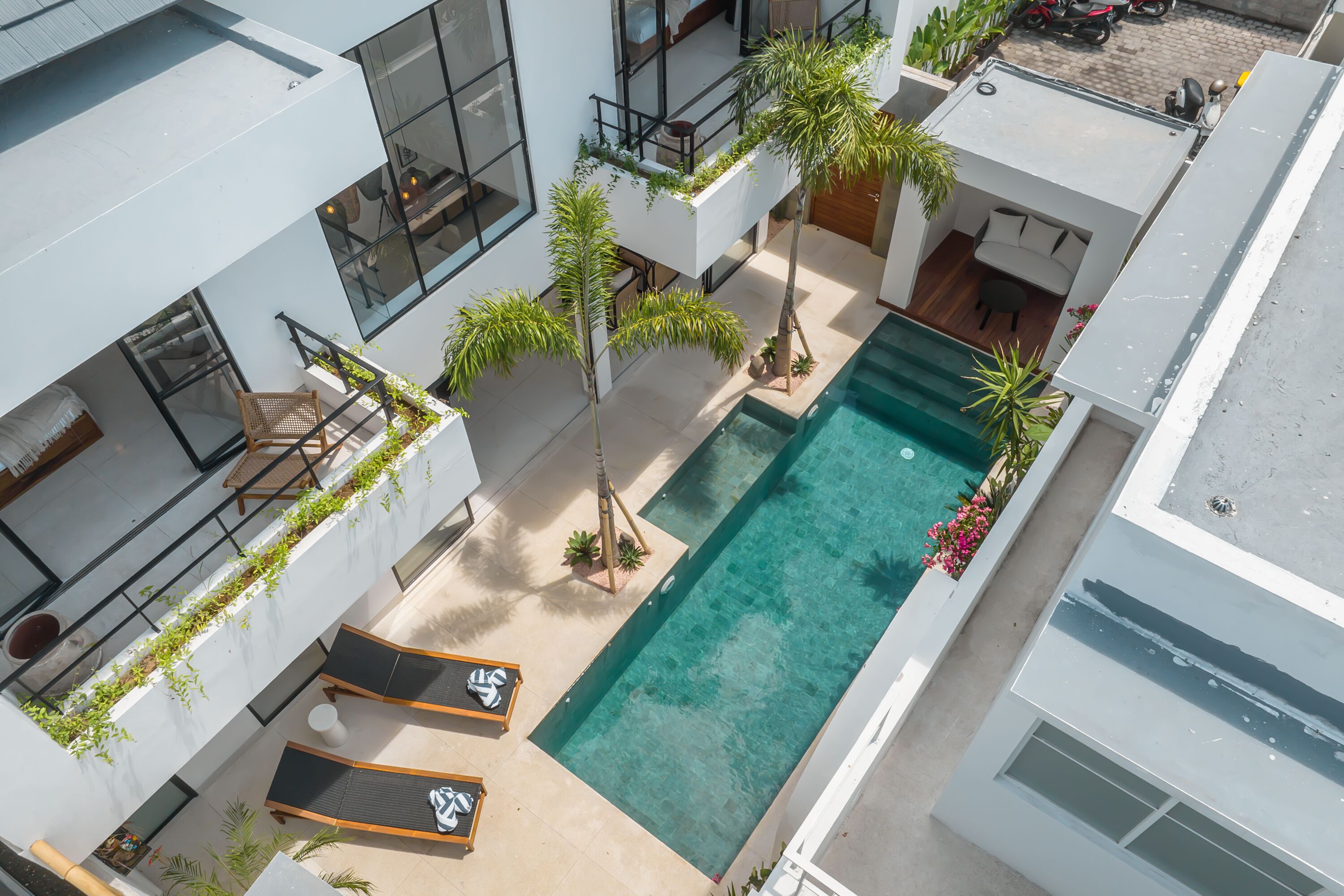 Un bâtiment moderne doté d’une piscine sur le toit, d’un espace extérieur aménagé et de verdure.