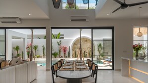 Un espace repas moderne avec une table ronde, des chaises noires et une cloison en verre.