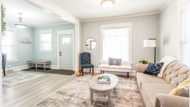 A spacious living room with a light blue wall, a beige sofa, a round coffee table, and a blue armchair. - Serenity Sauna Retreat - Blocks from Downtown (Sioux Falls)