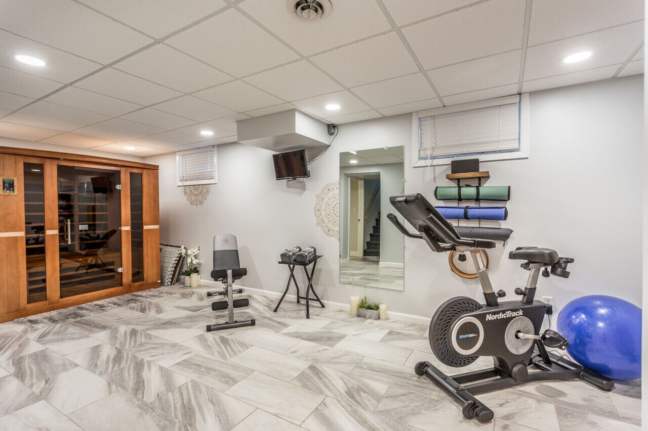 A home gym with a stationary bike, exercise ball, and weight bench.