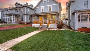 A two-story residential house with a front porch, a small front yard, and a driveway. - Serenity Sauna Retreat - Blocks from Downtown (Sioux Falls)