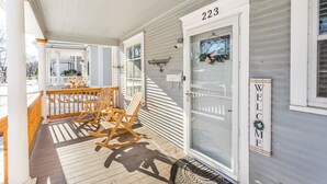 A porch with rocking chairs, a welcome sign, and a door marked with the number 223. - Serenity Sauna Retreat - Blocks from Downtown (Sioux Falls)