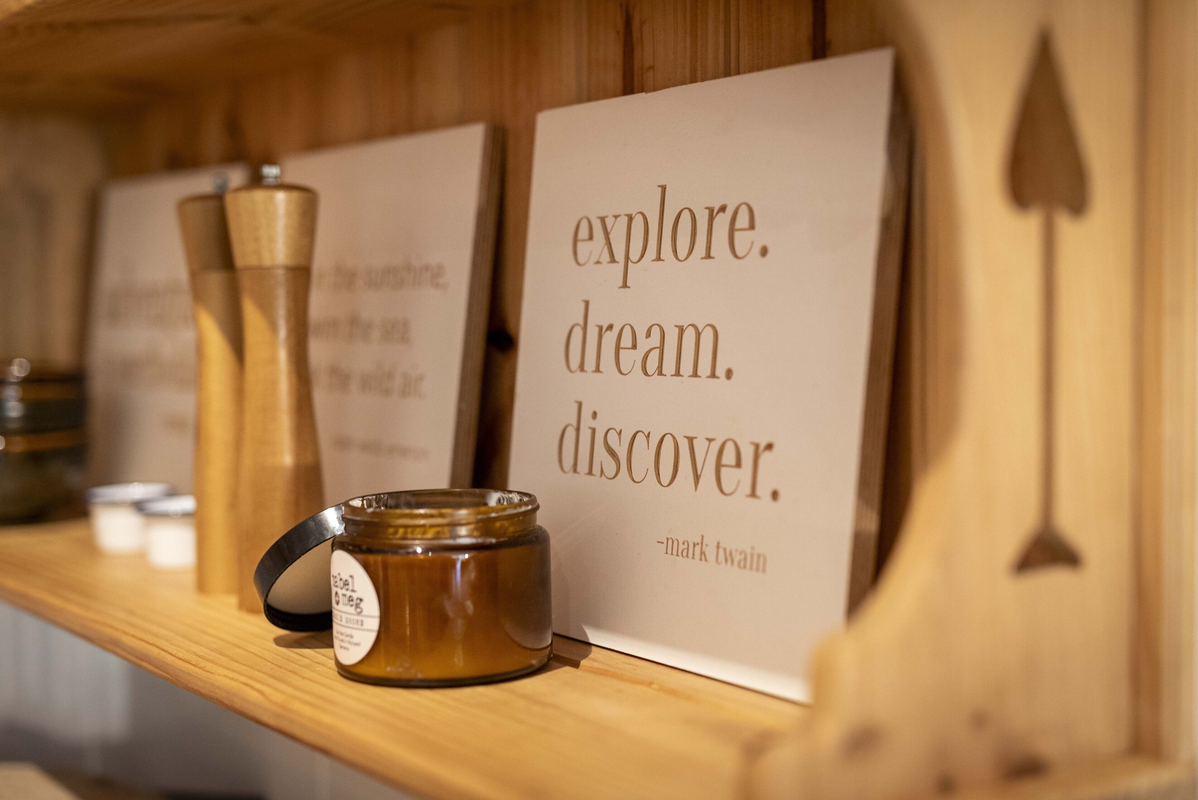 A wooden shelf with a candle, a jar, and a motivational quote sign.