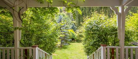 A covered garden area with white railings and a view of a lush green landscape.