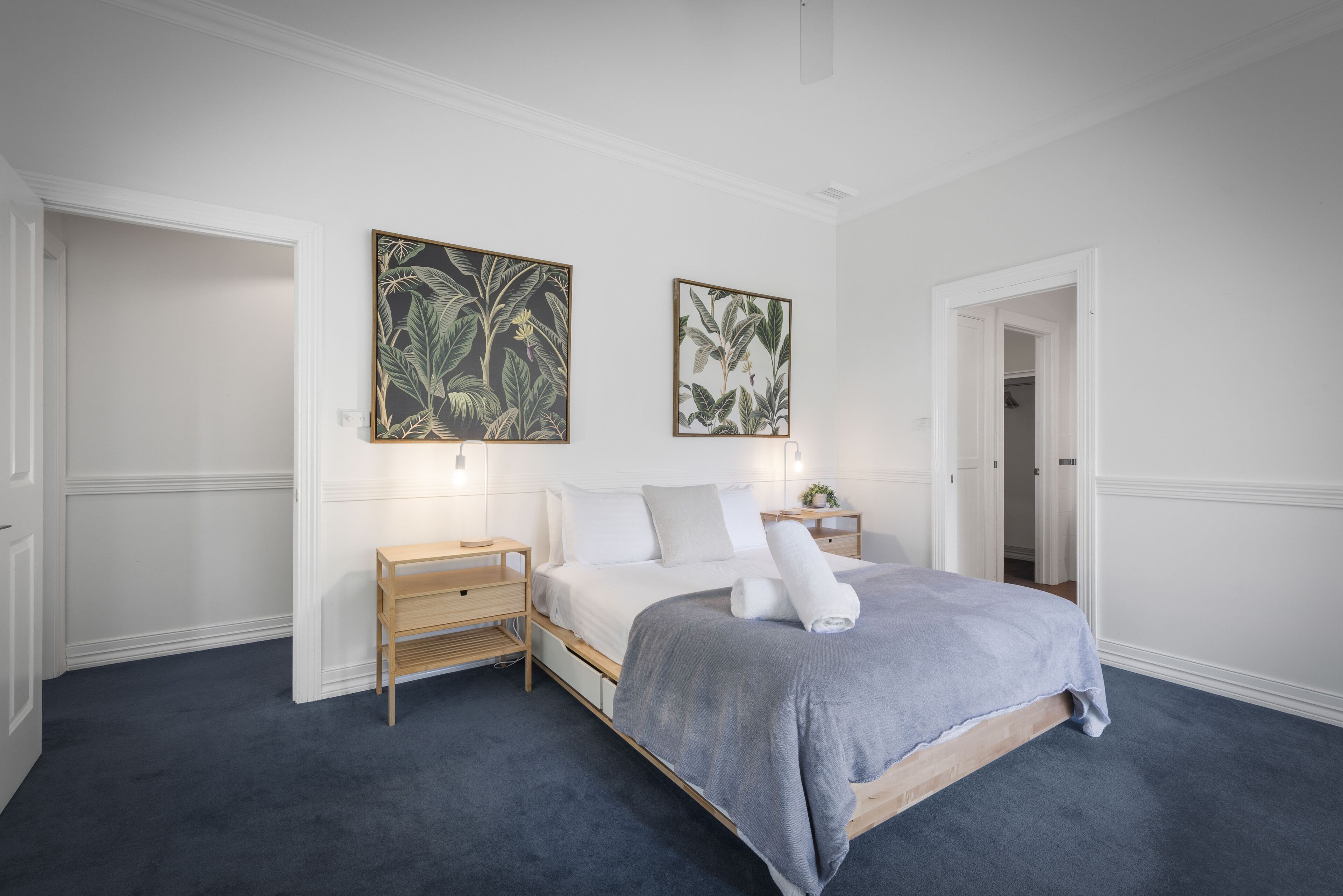 Ein Schlafzimmer mit einem Bett, Nachttischen und zwei an der Wand hängenden Bildern.