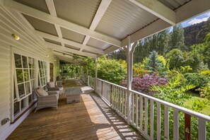 Relax on the covered porch with wicker furniture, taking in the serene views of the lush garden and hillside.