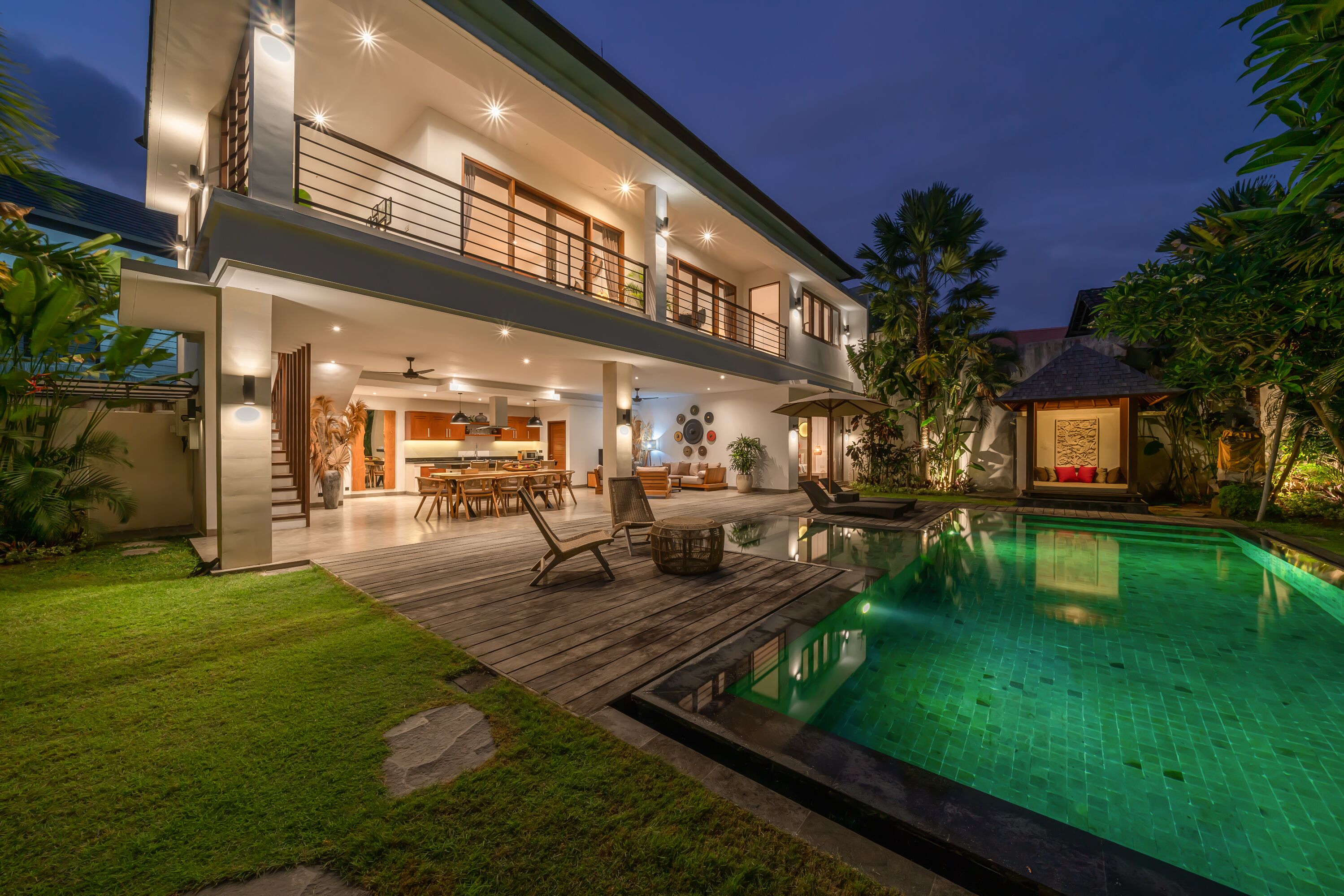 A modern two-story house with a swimming pool, outdoor seating, and a well-maintained garden.