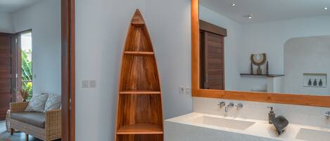 A bathroom with a wooden shelf, a large mirror, and a white sink.