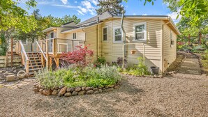 Une maison de plain-pied dotée d’un porche abrité, d’un petit jardin agrémenté de diverses plantes et d’une allée gravillonnée.