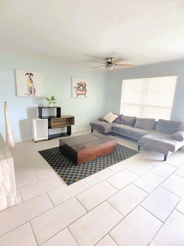 A living room with a sofa, a coffee table, a TV stand, and artwork on the walls.