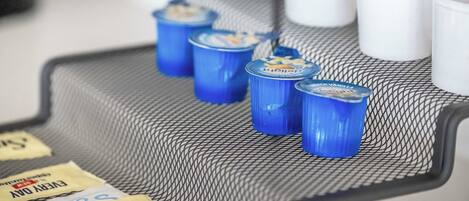 A tray with several beverage containers, some with blue lids and others with white lids, on a textured surface.