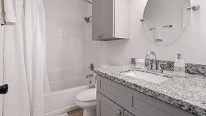 Une salle de bain équipée d’une douche, de toilettes, d’un lavabo et d’un miroir.