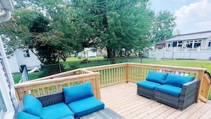 Eine Holzterrasse mit Korbmöbeln und blauen Kissen.