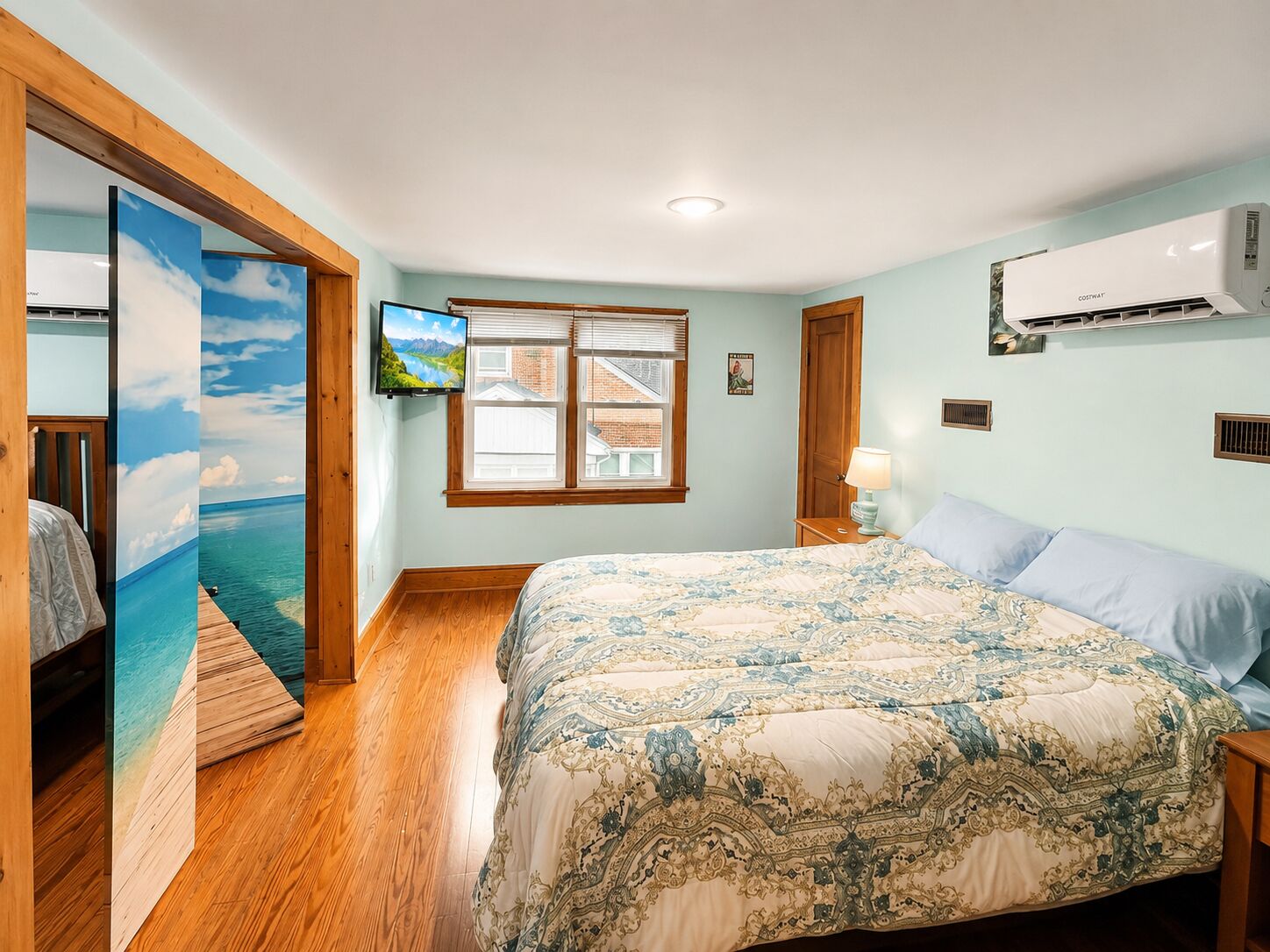 Une chambre à coucher avec un lit, une télévision, une fenêtre et un climatiseur.