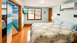 Ein Schlafzimmer mit einem Bett, einem Fernseher, einem Fenster und einer Klimaanlage.