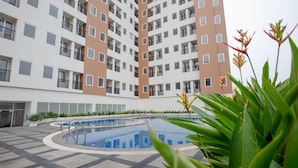 A modern building with a swimming pool surrounded by a tiled deck. - Praya Room (South Tangerang)