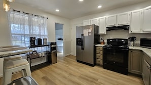 A modern kitchen with white cabinets, stainless steel appliances, and a wooden floor.