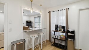 A modern kitchen with a countertop, bar stools, a coffee machine, and a refrigerator.