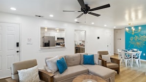 A modern living room with a sectional sofa, a round coffee table, and a dining area with a table and chairs.