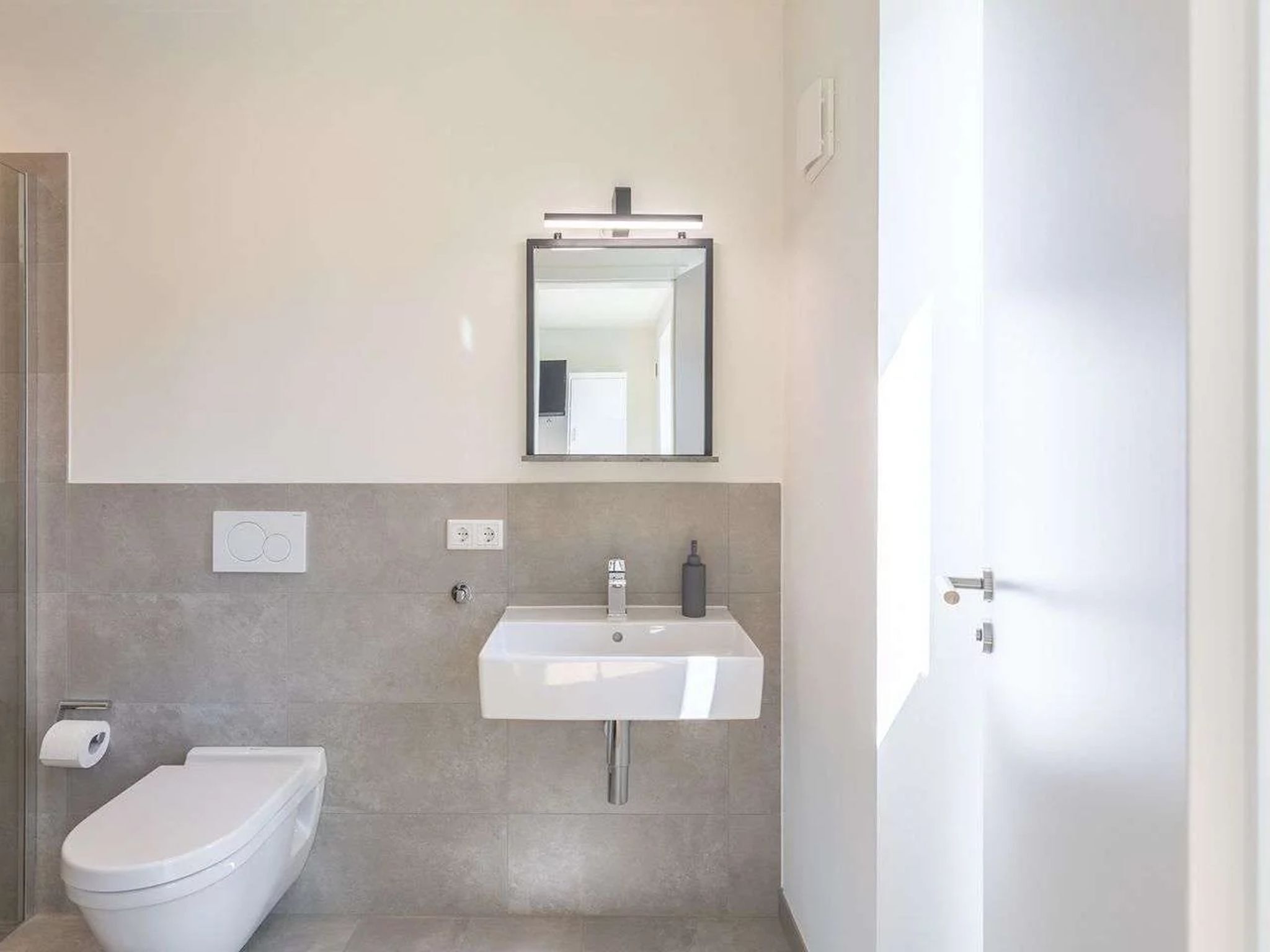 Ein modernes Badezimmer mit Toilette, Waschbecken und Spiegel.
