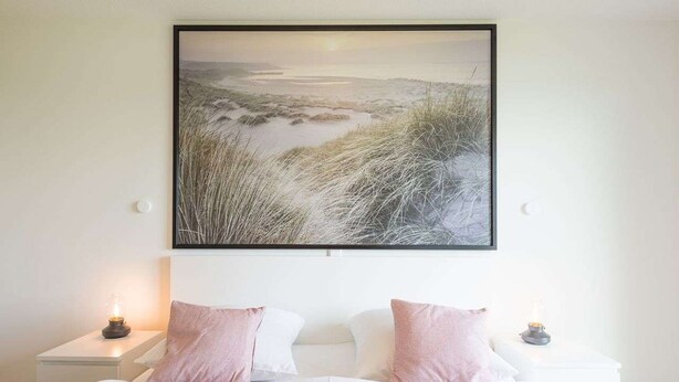 A bedroom with a large bed, two bedside tables, and a framed landscape painting above the bed. - Liselotte by Interhome (Nordstrand)