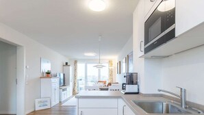 Une cuisine moderne avec des meubles blancs, un four encastré et un évier en acier inoxydable.