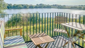 Eine Terrasse mit Tisch und Stühlen mit Blick auf einen See.