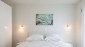 Ein modernes Schlafzimmer mit einem großen Bett, zwei Nachttischlampen und einem Wandbild.