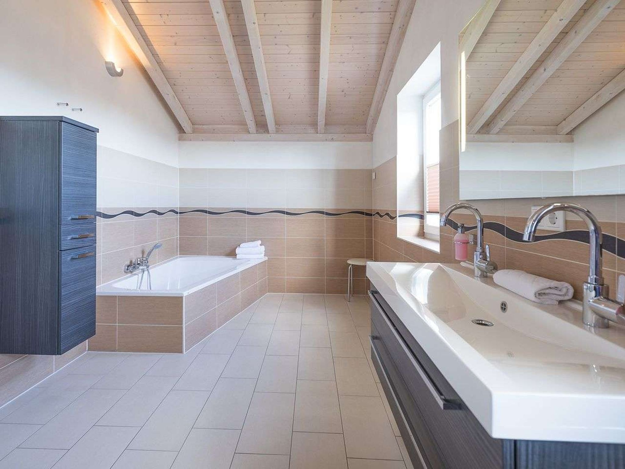 Une salle de bain moderne avec une baignoire, un grand lavabo et un meuble-lavabo.
