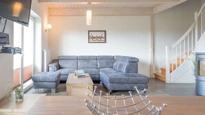 A modern living room with a grey sectional sofa, a wooden coffee table, and a metal rack. - Basstölpel by Interhome (Dagebüll)