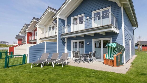 A two-story house with a balcony, a patio with chairs, and a small pool area. - Basstölpel by Interhome (Dagebüll)