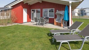 A red building with a covered patio, outdoor seating, and a blue umbrella.