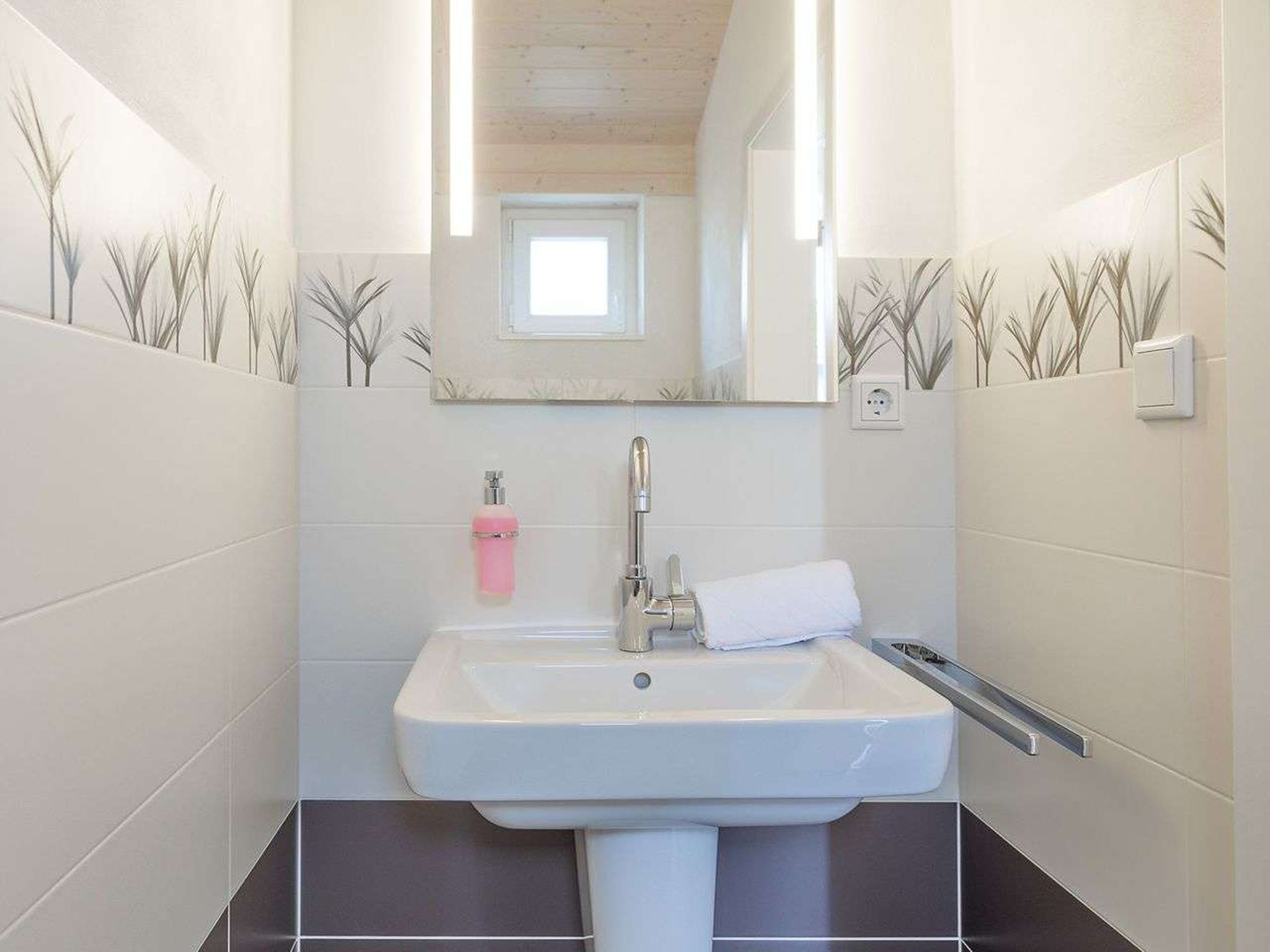 Une salle de bain avec un lavabo blanc, un miroir et une serviette.