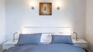 A bedroom with a bed, two bedside tables, a headboard, and two wall-mounted lamps. - Wattschnecke by Interhome (Dagebüll)