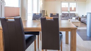 Un salon moderne avec une table à manger en bois, des chaises en cuir noir et un canapé gris.
