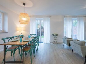 A dining area with a wooden table, green chairs, and a hanging light fixture.