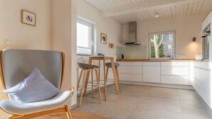 A modern kitchen with white cabinets, a wooden dining table, and two bar stools.