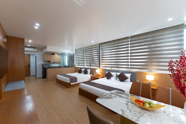 Una habitación de hotel moderna con dos camas, una zona de comedor y una kitchenette.
