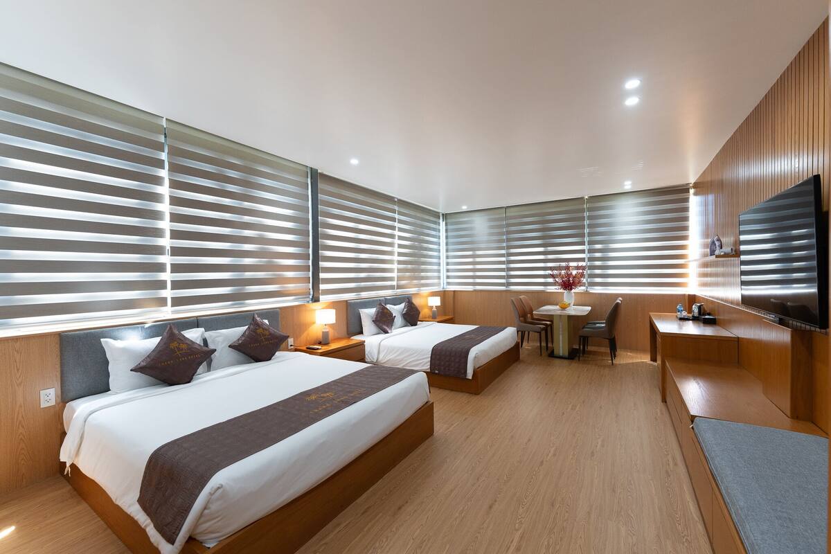 Ein modernes Hotelzimmer mit zwei Betten, einem Schreibtisch und einem Fernseher.