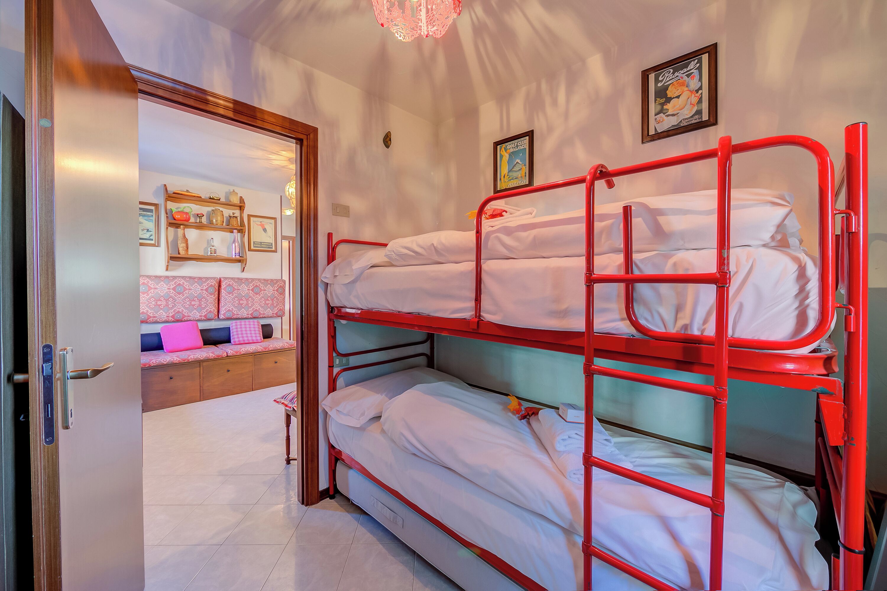 Una habitación con una litera, un banco de madera con cojines y una pared decorada con cuadros.