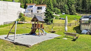 A playground with swings and a climbing structure, a picnic table, and a bench. - Apart Dawin by Interhome (Strengen)