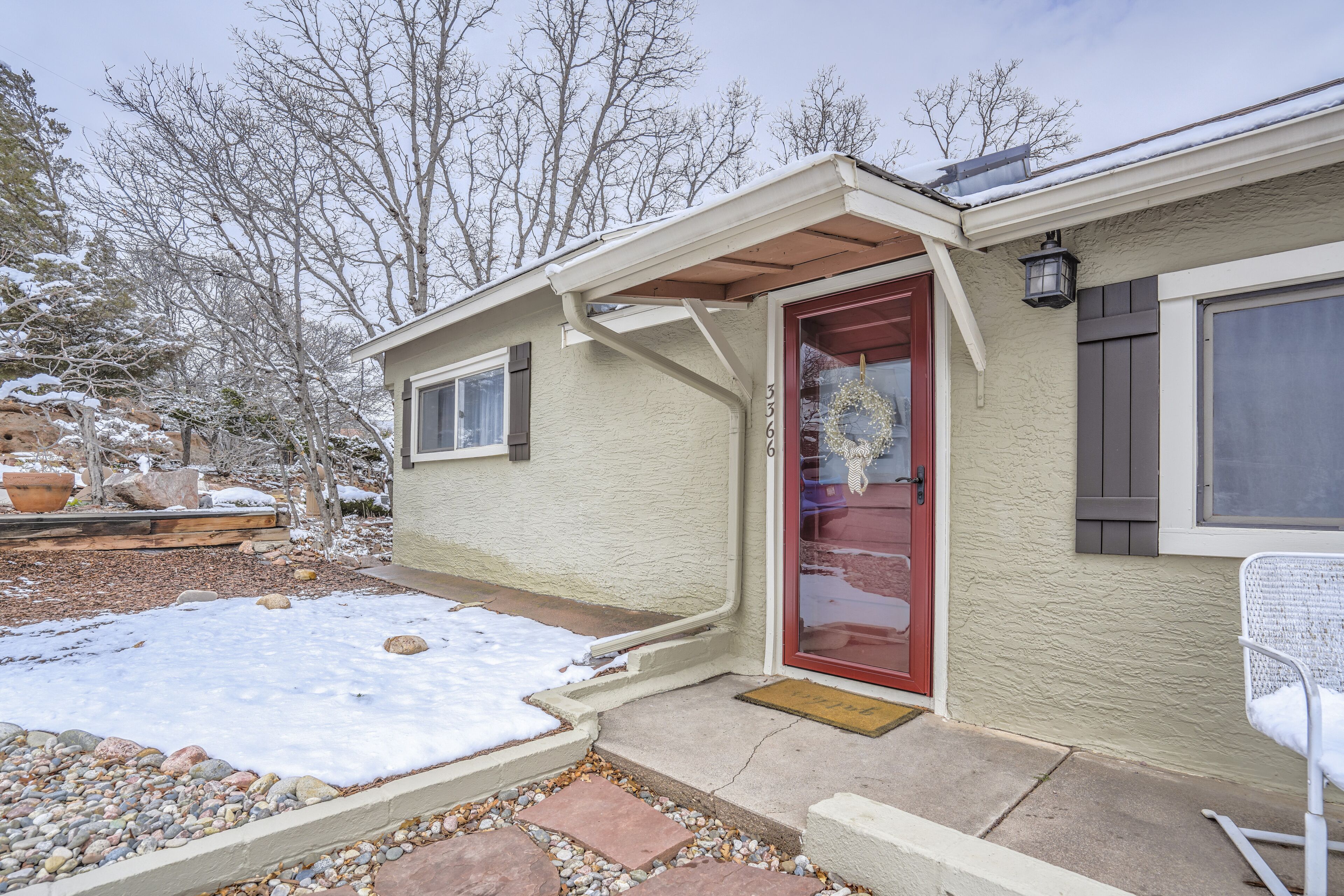 A house with a red door, a small porch, and a snow-covered yard.