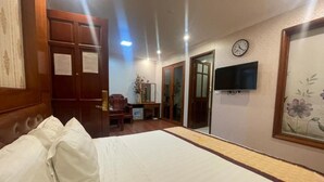 A hotel room with a bed, a television, a clock, and a door. - Ngoc Lan 2 Hotel- by Bay Luxury (Hanoi)