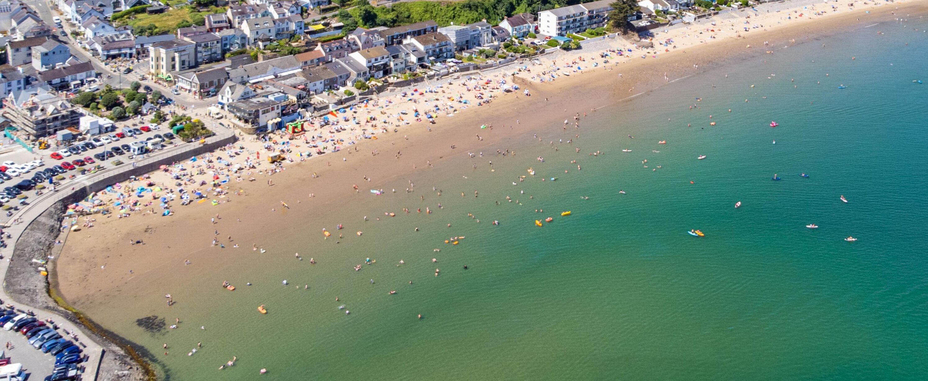 Une vue aérienne d’une plage bordée d’une rangée de bâtiments le long du rivage.