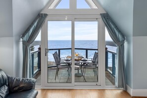 A room with a large sliding glass door leading to a balcony with a view of the sea. - Schooner House - Panoramic Sea Views and Parking (Saundersfoot)