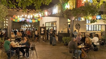 Un espace extérieur aménagé pour les repas, avec des tables et des chaises, entouré d’une cour pavée de briques.