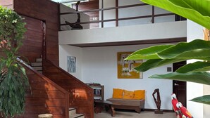 A spacious indoor area with a wooden staircase, a sofa with orange cushions, and a parrot statue. - SamaraChilloutLodge (Sámara)