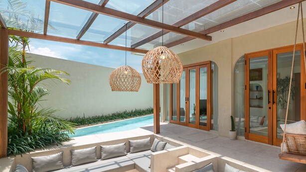 Ein moderner Außenloungebereich mit Pool, gepolsterten Sitzgelegenheiten und hängenden Korblampen.