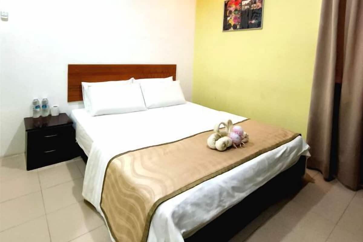Ein Hotelzimmer mit einem Bett, einem Nachttisch, einem Wandbild und einem Vorhang.