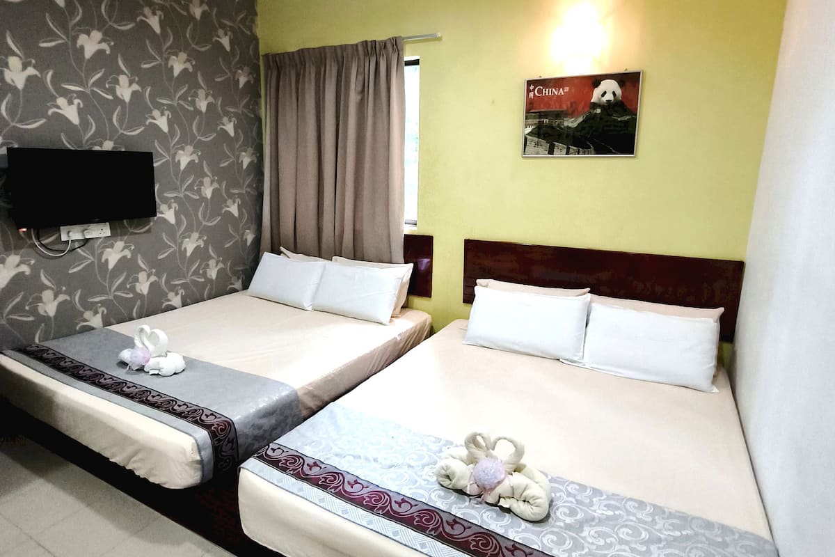 Ein Hotelzimmer mit zwei Betten, einem an der Wand befestigten Fernseher und einem Poster mit einem Panda.